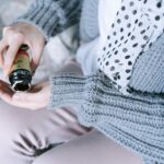 Close-up of a woman in cozy clothing holding a medicine bottle in her hands.